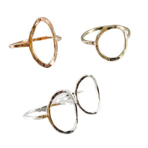 three rings on a white background. leaf shaped ring in the upper left, circle shaped ring in the upper right and two oval shaped rings on the bottom.