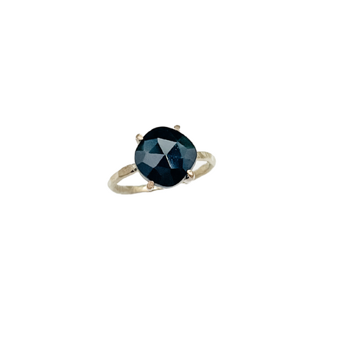black spinel ring with a gold setting sitting upright on a white background